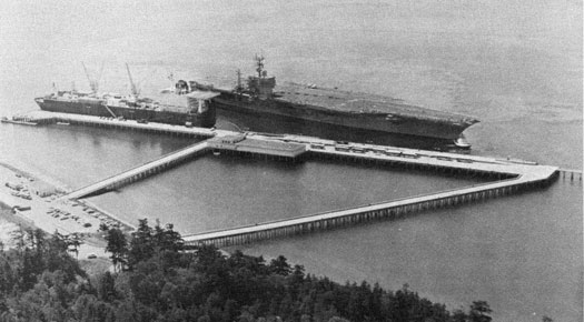 The USS Nimitz is guided into place alongside the pier.