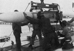 Riggers load a standard missile onto a guided missile frigate.