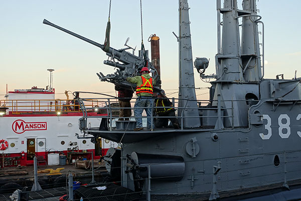 gun being lowered by crane onto boat
