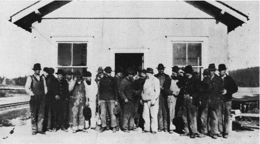 Photo of a group of workmen outside a small building.
