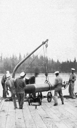 Torpedo being loaded with a davit onto a small torpedo carriage.