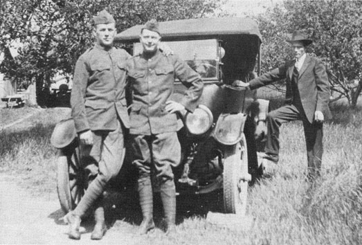 Two marines and a friend posed in front of a car.
