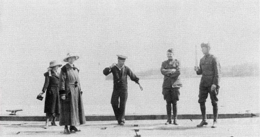 A young sailor dances before two woman and two soldiers.