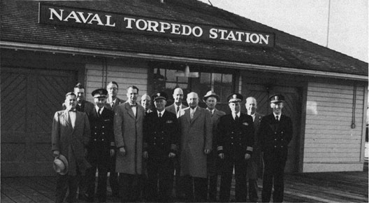 A group of men posed in front of the Naval Torpedo Station.
