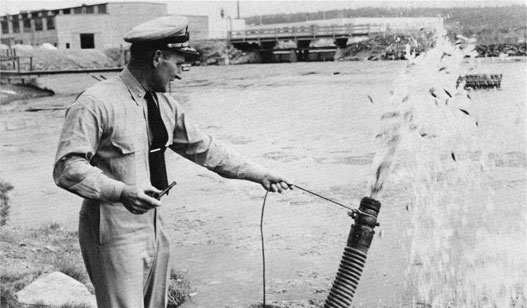 Officer smiling as water and fish shoot out of a hose.