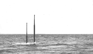 Photo of periscopes from a submerged submarine breaking through the water.